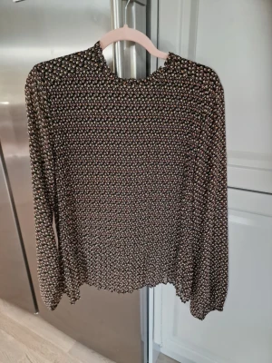 Blommig långärmad blus. - Söt blus med småblommigt mönster.. Blusen har lång ärm och en lätt rynkad hög krage. Materialet är tunt och flowy, perfekt för en trendig look. Använd 2 gånger. I mycket bra skick. 