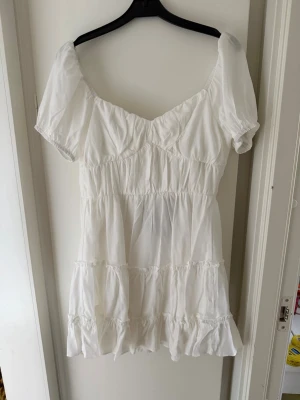 Studentklänning  - Söt vit kort klänning med puffärmar och volanger. Köpt för studenten men ej använd 