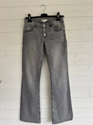 Grå bootcut jeans - Snygga grå bootcut jeans med låg midja. Jeansen har fickor framtill och baktill, samt justerbar midja. Strl: 158 barnstorlek