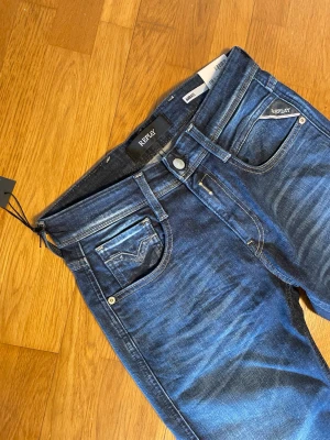 Mörkblå skinny jeans från Replay - Snygga mörkblå skinny jeans från Replay med klassisk femficksdesign och diskreta slitningar. Jeansen har en smal passform och är tillverkade i stretchigt denim för extra komfort. Perfekta för en trendig och avslappnad look.