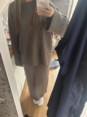 Brunt stickat set med lång kjol - Säljer ett brunt stickat set som består av en oversized tröja med vida ärmar och en lång, rak kjol med resår i midjan. Setet är i mjukt material och har en enkel, stilren design som passar perfekt för en avslappnad look.