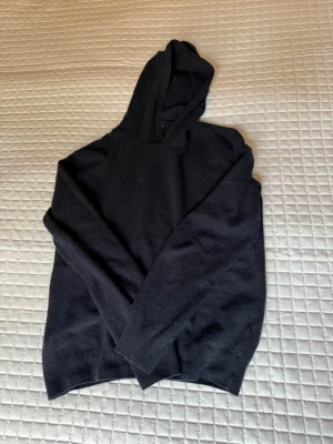 Mörkblå kashmir hoodie från Oscar Jacobson - En stilren mörkblå hoodie från Oscar Jacobson i kashmir. Klassisk passform med huva och långa ärmar. Perfekt för dig som gillar en clean och enkel look. Materialet känns skönt mot huden och funkar till det mesta.