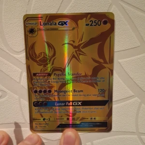 Lunala GX Pokémonkort guld - Säljer ett exklusivt Lunala GX Pokémonkort i guldutförande med holografisk finish. Kortet har 250 HP och flera specialattacker som Psychic Transfer, Moongeist Beam och Lunar Fall GX. Perfekt för samlare eller Pokémonfans som vill ha något unikt i sin samling.