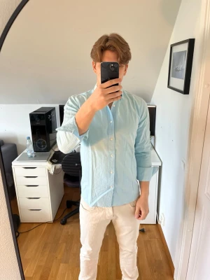 Ljusblå skjorta från J.Lindeberg - Säljer en stilren ljusblå skjorta från J.Lindeberg i 100% bomull i regular fit. Skjortan har klassisk krage. Det följer även med 3 extra knappar. Hör gärna av dig vid frågor!