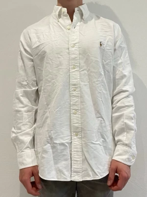 Vit skjorta från Ralph Lauren - Ralph Lauren skjorta || Storlek M (Custom Fit) || Skjortan är i bra skick || Modellen på bilden är 170cm och väger 62kg || Tveka inte på att höra av dig vid frågor eller funderingar 