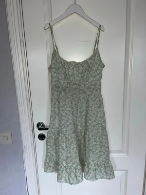 Grön blommig sommarklänning - Söt grön klänning med vita små blommor och volangkant nertill. 