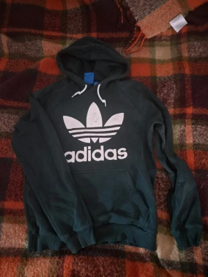 Mörkgrön Adidas hoodie med stor logga - Snygg mörk grön hoodie från Adidas med logga på bröstet. Storkek M
