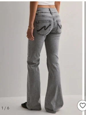 Grå bootcut jeans från Nelly - Snygga grå bootcut jeans från Nelly i storlek 38 med svarta broderade detaljer på bakfickorna. Säljes då de inte längre kommer till användning. De är i fint skick och sitter jättefint. Vid intresse eller om du vill ha fler bilder är det bara att skriva 💕