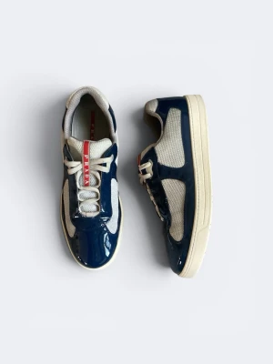 Prada skor - Snygga sneakers från Prada med blankt blått skinn och vita meshpaneler. Skorna har vita snören, en vit sula och en röd logga på plösen. Perfekt för dig som vill ha en stilren och exklusiv look med sportig känsla.