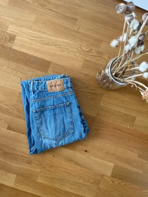 Blå baggy jeans från Pull&Bear - Säljer ett par ljusblå baggy jeans från Pull&Bear. Klassisk femficksmodell med hög midja och avslappnad passform. Tillverkade i denim med snygg tvätt och detaljerade sömmar. Perfekta för en chill och trendig look.