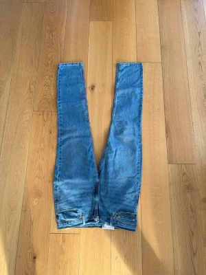 Levi's blå raka jeans - Klassiska blå jeans från Levi's med rak passform och femficksdesign. Jeansen har en tydlig Levi's-lapp bak i midjan och är tillverkade i slitstark denim. Perfekta för en avslappnad och tidlös look.