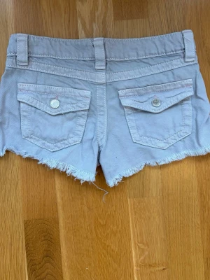 Ljusgråa fransiga Jeansshorts med knappfickor från Gina Young - Köpte dessa shorts från Vinted, de var originellt rosa men på grund av att säljaren tvättade de fel så blev de missfärgade. Missfärgningen är rätt så jämn och syns inte, har själv haft på mig de några gånger men har växt ut ur de nu. Katt finns i hemmet, skriv om ni har frågor. 