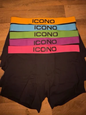 Svarta kalsonger från ICONO med färgglada resår - Säljer ett flerpack oanvända  svarta kalsonger från ICONO med bred resår i olika färger: gul, blå, grön, lila och rosa. Kalsongerna har en klassisk passform och är tillverkade i mjuk bomull för maximal komfort. Perfekta för dig som gillar färg och stil även på underkläder. 