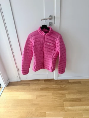 Rosa dunjacka från Everest - Snygg rosa dunjacka från Everest med quiltad design och hög krage. Jackan har dragkedja framtill och är lätt vadderad för extra värme. Perfekt för kalla vinterdagar och riktigt skön att bära.