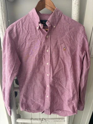 Ralph Lauren Skjorta  - Ralph lauren skjorta Rosa, använd ett par gånger, har en fläck på ryggen men som inte märks😊storlek M mycket bra skick, mått: längd=73cm från kragen bredd≈52cm snabb frakt✅ tar gärna emot frågor, bud osv
