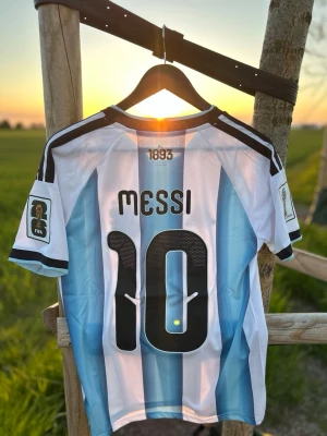 Argentina Messi matchtröja Adidas- strl M - Säljer en sprillans ny och oanvänd  Argentina fotbollströja från Adidas med Messi och nummer 10 på ryggen. Tröjan har klassiska blå och vita ränder, svarta detaljer och FIFA-märke på ärmen. Perfekt för dig som älskar fotboll och vill stötta landslaget. Storlek M. Snygg fit och bra skick.