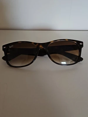 Snygga Ray-Ban New Wayfarer brunmelerade solglasögon - Snygga Ray-Ban New Wayfarer RB 2132, I mycket bra skick.. Klassisk fyrkantig form som ger en cool och tidlös look.  Pris kan diskuteras.