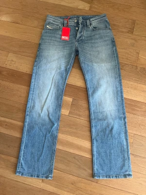 Ljusblå raka jeans från Diesel - Snygga ljusblå jeans från Diesel med raka ben och klassisk femficksdesign. Jeansen har en diskret tvättad look och silverfärgade knappar. Perfekta för en avslappnad och trendig stil.