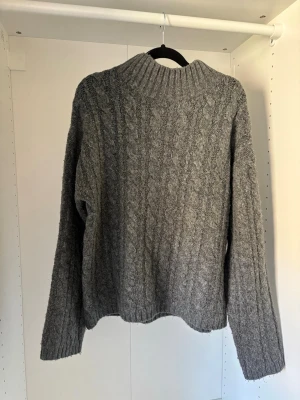 Grå kabelstickad tröja - Använd fåtal gånger, börjar bli lite nopprig vilket syns på bilderna.