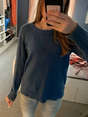 Blå stickad tröja med rund hals - En enkel och snygg blå stickad tröja med rund halsringning och långa ärmar. Tröjan har ribbstickade muddar vid ärmslut och nederkant. Perfekt att slänga på sig när det är lite kyligt ute.