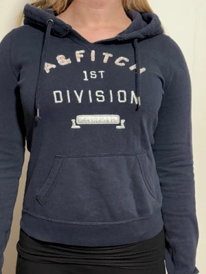 Mörkblå hoodie Abercrombie & Fitch - En mörkblå vintage hoodie med ett snyggt tryck som de ät lite glitter på texten A & Fitch. Märket är Abercrombie & Fitch. Storlek S. Skick 9/10. Skriv vid frågor.