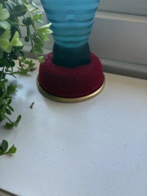 Jean Paul Gaultier Le Male parfym - Säljer en ikonisk parfymflaska från Jean Paul Gaultier, Le Male. Flaskan är formad som en manlig torso i blått glas med horisontella ränder. Den står på en rund röd sammetsbas med guldkant. Perfekt för dig som gillar unika och snygga parfymflaskor. Köpt med 40 ml ungefär 25 ml kvar 