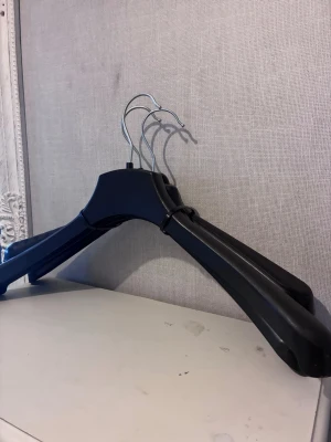 3st svarta galgar i plast och metall - Säljer ett set med tre svarta galgar i kraftig plast med metallkrokar. Perfekta för att hänga upp jackor, kavajer eller andra plagg. Galgarna har breda axlar och en stilren design som passar i alla garderober.