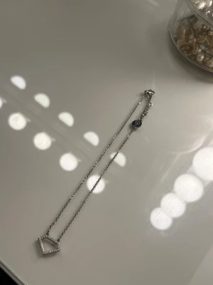 Edblad silverhalsband - Snyggt halsband i silverfärg med en geometrisk, diamantformad berlock dekorerad med små gnistrande stenar. Sparsamt använd i fint skick. Från Edblad 