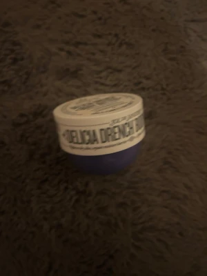 Sol de Janeiro Brazilian Drench Body Butter - Lila burk med vit etikett från Sol de Janeiro, Brazilian Drench Body Butter. Perfekt för dig som vill ha återfuktad och mjuk hud. Smidig att ta med i väskan och enkel att applicera.