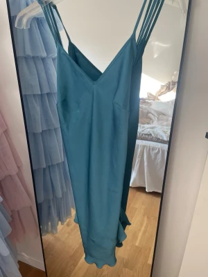 Turkost nattlinne med smala axelband - Snyggt turkost nattlinne i satinliknande material med dubbla smala axelband och v-ringning både fram och bak. Baktill finns en fin spetsdetalj. I ryggen är typ omlott☺️