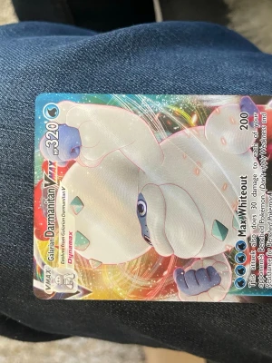 Pokémonkort Galarian Darmanitan VMAX - Säljer ett Pokémonkort med Galarian Darmanitan VMAX. Kortet har en färgglad, holografisk yta och visar en isblå och vit Pokémon i dynamisk pose. Kortet har 320 HP och attacken Max Whiteout. Perfekt för samlare eller Pokémonfans.