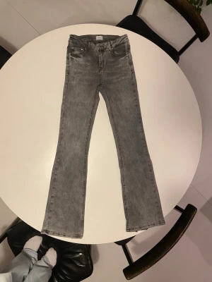 Gråa bootcut jeans från Grunt - Snygga gråa bootcut jeans från Grunt med klassisk femficksdesign och bälteshällor. Jeansen har en tvättad look och är tillverkade i mjukt denimtyg med stretch för extra komfort. Perfekta för en avslappnad och trendig stil. Passar xxs/xxxs 💕