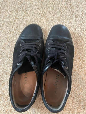 Lanvin Nappa Captoe Sneaker svart - Snygga Lanvin Nappa Captoe sneakers i svart läder med klassisk captoe-design. Skorna har en stilren och modern look med exklusivt materialval i nappa. Perfekta för dig som vill ha en lyxig sneaker med tidlös känsla och premiumdetaljer.