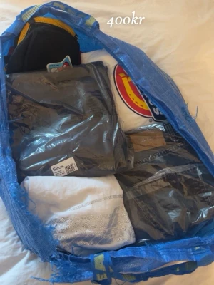 Klädpaket med blandade plagg - Säljer ett stort klädpaket i en blå IKEA-kasse med flera olika plagg/märkeskläder bas plagg. Bland annat snygga Hugo Boss byxor mm.