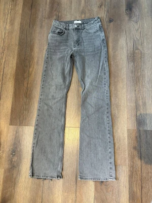 Grå raka jeans från Gina Tricot - Säljer ett par grå jeans med rak passform och rå kant nedtill. Jeansen har klassisk femficksdesign och normal midja. Perfekta till en avslappnad stil och passar till det mesta. Materialet är denim i bomull. Defekt! Slitna längst nere på baksidan av byxornas ben!💓🌸