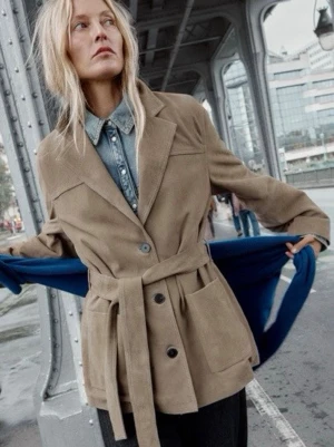 Brun trenchcoat med knytskärp från Zara 100%leather - Snygg beige trenchcoat från Zara 100%leather  med knytskärp i midjan och stora fickor framtill. Jackan har klassisk krage och två knappar, perfekt för lager-på-lager och streetstyle. Materialet är mjukt och matt, vilket ger en avslappnad men stilren look. Ord pris 3795kr