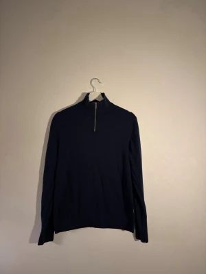 Mörkblå halvzip från Jack & Jones - Mörkblå tröja från Jack & Jones med halv dragkedja och hög krage. Tröjan har lång ärm och är tillverkad i mjukt material som passar perfekt till lager på lager. Enkel och stilren design som funkar till det mesta.