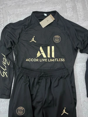 Helt ny fotbolls tracksuit - Väldigt fin guld och svart psg tracksuit, helt ny och oanvänd, skön för sommarn. Skriv vid inteesse!