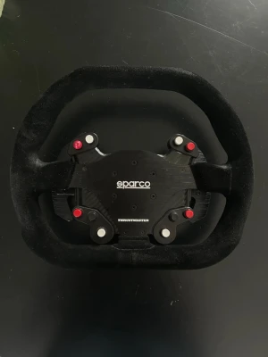 Sparco ratt från Thrustmaster - Säljer en Sparco racingratt från Thrustmaster med svart mocka och robust design. Ratten har flera knappar och paddlar för gaming, perfekt för simracing och racing-spel. Materialet är högkvalitativt och ratten har en sportig, oval form.