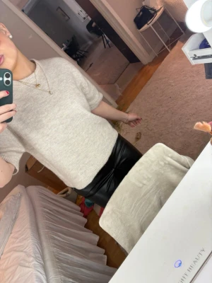 Beige stickad kortärmad tröja - Säljer en beige stickad tröja med korta ärmar och rund hals. Tröjan har en avslappnad passform och är gjord i ett mjukt material som känns skönt mot huden. Perfekt att styla med både jeans och kjol för en clean look. Från Gina! 