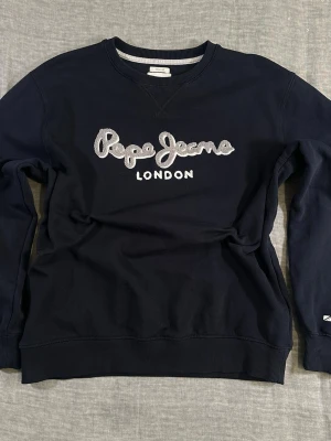 Pepe Jeans London Spell Out Crewneck XL Navy Embroidered Logo Y2K 90s Streetwear Oversized - Pepe Jeans London crewneck in deep navy with large embroidered spell-out logo across the chest. Midweight 100% cotton fleece with solid structure. Size XL (works oversized on L). Clean 90s / y2k streetwear vibe. Easy to style with baggy denim or cargos. Good used condition, no major flaws. See measurements in photos for best fit. 