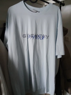 Ljusblå Givenchy t-shirt med tryck - Säljer en ljusblå t-shirt från Givenchy med tryck i blått och svart på både fram- och baksidan. Oversized passform och klassisk rund halsringning. Perfekt för dig som gillar streetwear och exklusiva märken. Självklart äkta. 