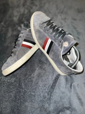 Grå Moncler skor i mocka - Hej, säljer ett par moncler skor för mycket bra pris. Om du inte vill köpa skor för 7000kr är dom här perfekta för dig sulornas matrial har försvunnit lite men inget som gör dom mindre bekväma. Man får också med ett par extra sulor om man skulle vela byta. Skorna har en fläck fram på en av skorna men går säkert att få bort men har inte haft den tiden . Sulan går också att göra mer rent . sulan och fläcken och att dom är lite solblekta påverkar pris såklart fast de är lätt fix,PRIS KAN DISKUTERAS