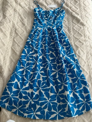Blåvit blommig sommarklänning XS Mango - Ny Snygg blåvit klänning med blommigt mönster och smala axelband. Klänningen har en lätt utställd form och är perfekt för varma dagar. Tillverkad i ett luftigt material som känns skönt mot huden. Perfekt för dig som vill ha en färgglad och fräsch look.