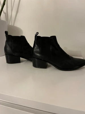 Svarta Chelsea boots i skinn. Vagabond  - Snygga svarta Chelsea boots i äkta skinn med klassisk resår på sidorna och dragflikar både fram och bak. Boots med rundad tå och stabil klack som ger lite extra höjd. Perfekta för dig som vill ha en stilren och tidlös look.