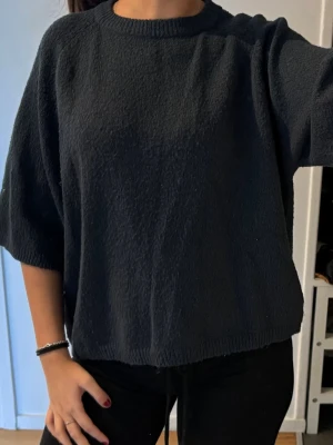 Mörkblå tröja med korta armar - Säljer en svart oversized tröja med rund halsringning och halvärmar. Tröjan har en mjuk, lite texturerad yta och avslappnad passform. Perfekt för dig som gillar en enkel men stilren look.