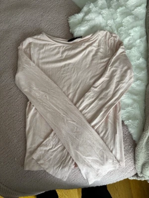Ljusrosa långärmad topp - En enkel och stilren ljusrosa långärmad topp med rund halsringning. Tillverkad i ett mjukt och tunt material som känns skönt mot huden. Är mer rosa i verkligheten. Storlek 170/ S