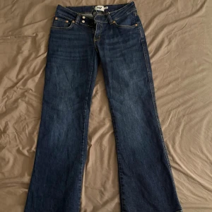 Mörkblå low waist bootcut jeans  - Snygga mörkblå low waist bootcut jeans från Lager 157 med orangea sömmar. Jeansen är i storlek S och short i längden. Dem är använda ett par gånger men är i ett bra skick.