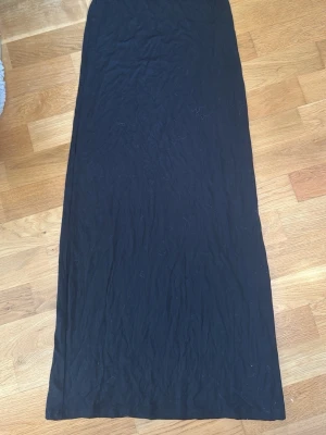 Svart långkjol i enkel design - En svart långkjol med rak passform och minimalistisk look. Kjolen är utan synliga detaljer och har en stilren siluett som passar till många olika outfits. Aldrig använd