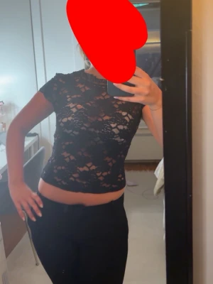 Svart spetsblus från Zara - Säljer en svart, croppad spetsblus från Zara. Toppen är genombruten med blommigt spetsmönster, har korta ärmar och en tight passform. Perfekt för dig som vill ha en trendig och snygg topp med det lilla extra.